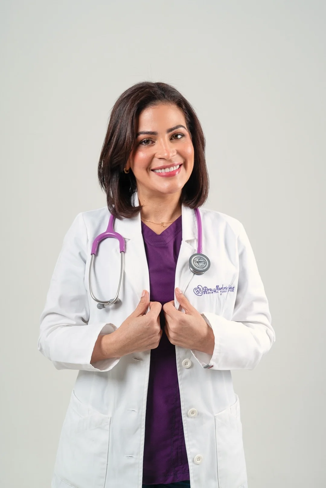 La doctora sonríe con bata y estetoscopio